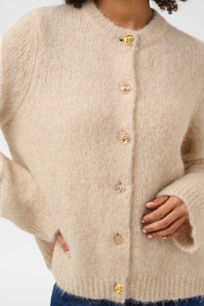 Kvinne i beige CULTURE Anthea cardigan, myk og komfortabel, vises på bilde, over dameklær.